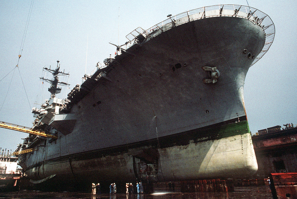 Navy personnel inspect damage to the hull of the amphibious assault ...