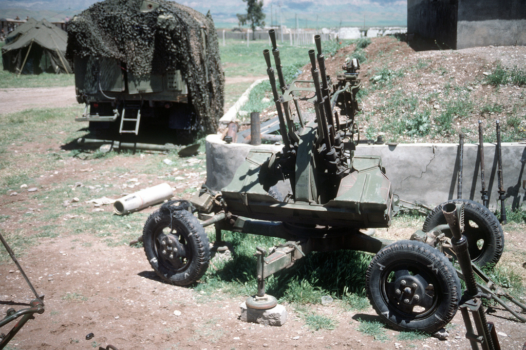 A Soviet-made ZPU-4 anti-aircraft gun stands in a holding area with machine gun barrels lining a wall. The weapons were confiscated by Marines during Operation Provide Comfort
