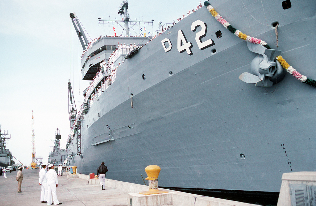 Crew members stand at the railing aboard the destroyer tender USS ...