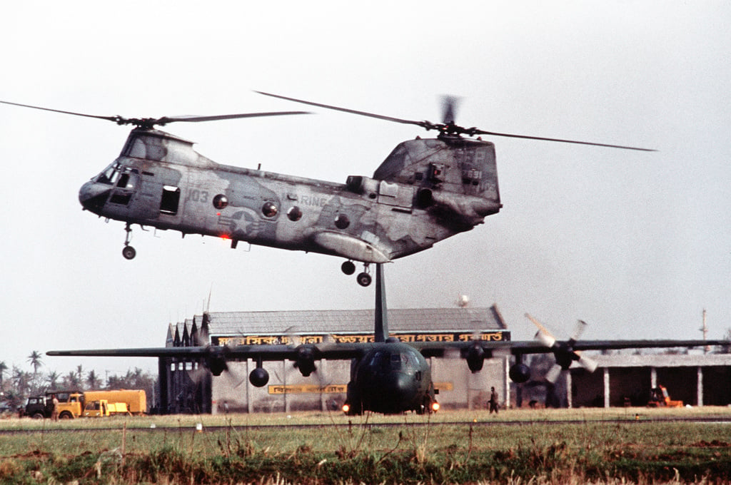 A CH-46 Sea Knight helicopter lands as a 374th Tactical Air Wing C-130 ...