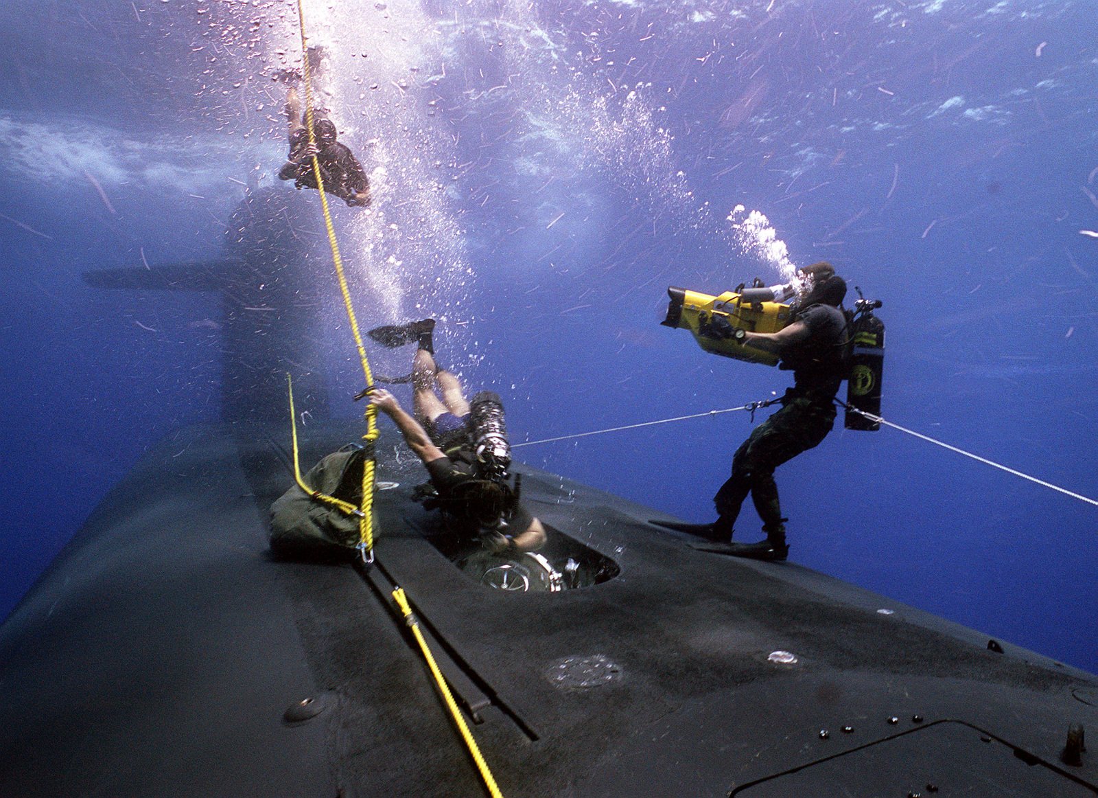 A member of a Navy sea-air-land (SEAL) team descends along a line as ...