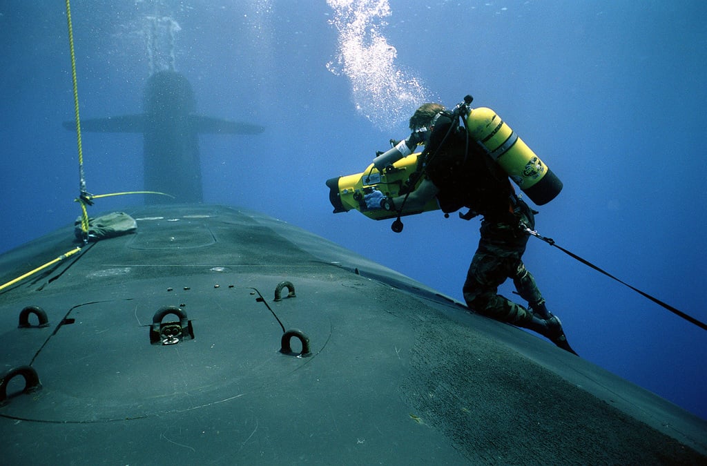 A photographer's mate/diver aims his camera at a hatch in the forward ...