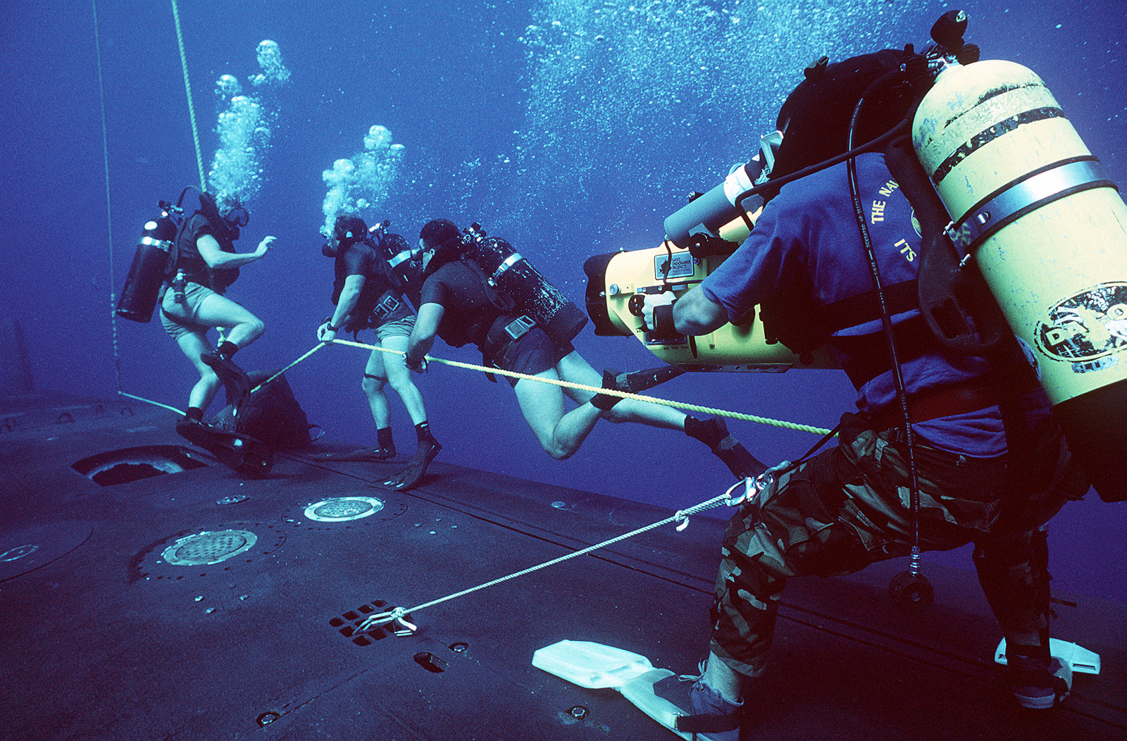 A photographer's mate/diver films the manuevers as members of a Na...