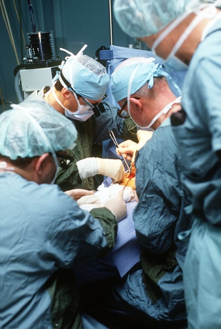 A surgical team headed by LT. CMDR. Randall Culp, with magnifying ...