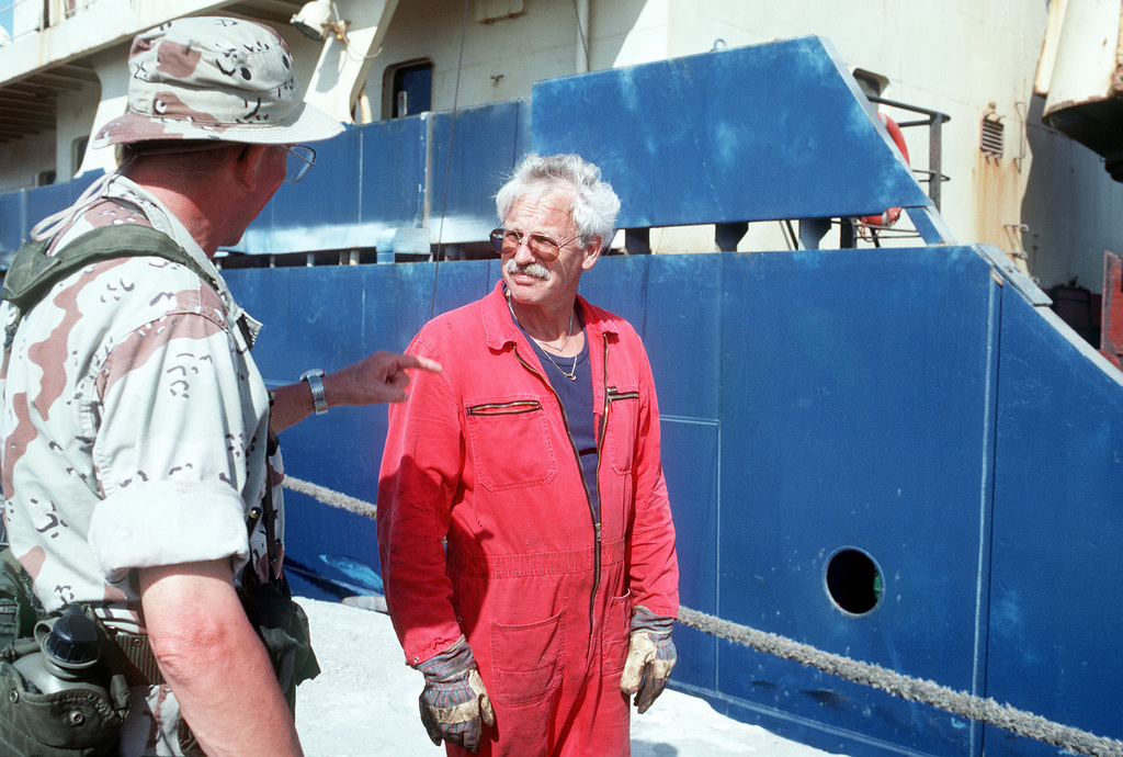 A Seabee Talks With A Civilian Worker Next To A Ship Moored In Port ...