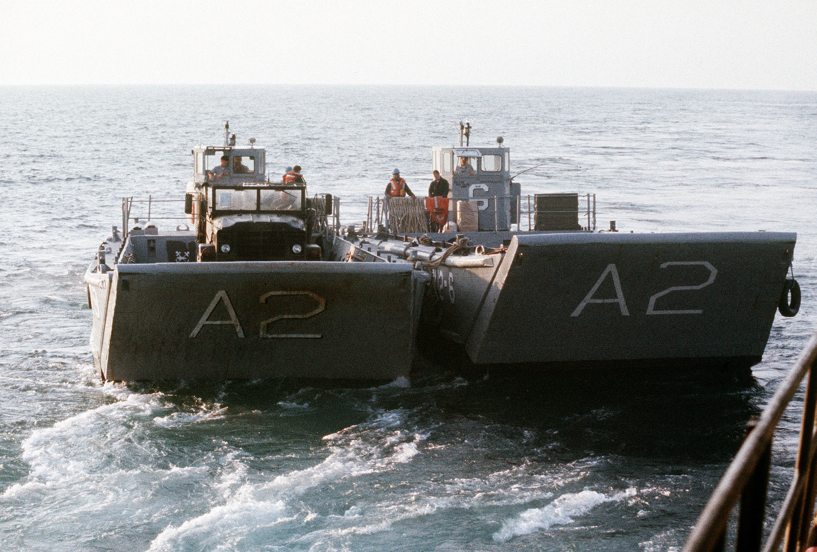 A pair of LCM-8 mechanized landing craft back away from an amphibious 