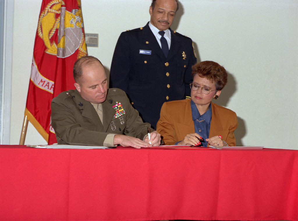 Mayor Sharon Pratt Kelly watches as Brig. GEN. Steele signs an