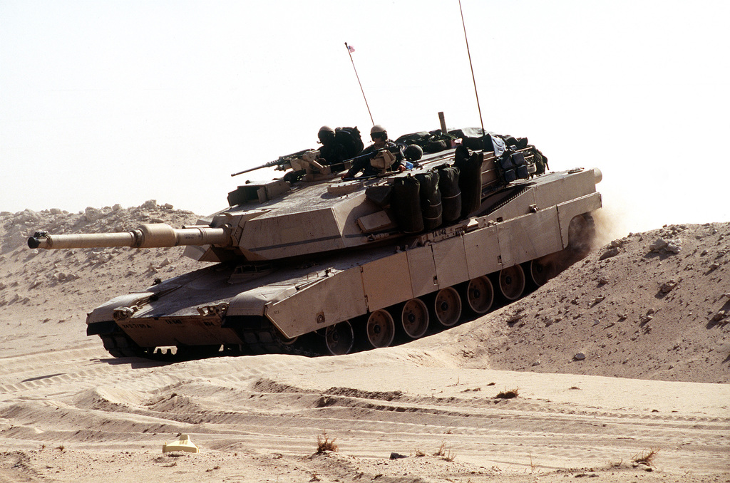 A M1A1 Abrams tank breaches a berm in the desert during maneuvers ...