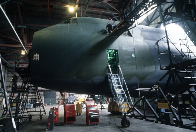 A camouflaged C-5A Galaxy aircraft in a hangar for inspection and ...