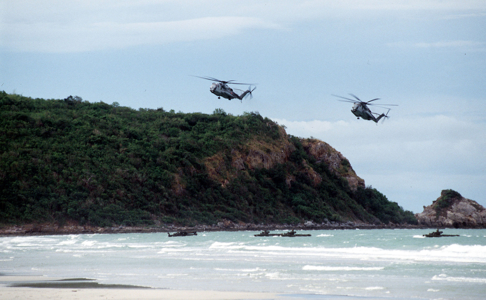 Two US Marine Corps CH-53's fly overhead as amphibious assault vehicles ...