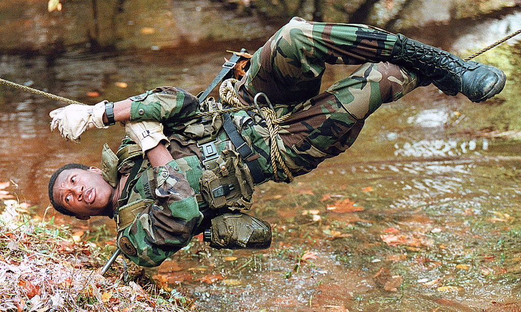An unidentified US Army (USA) Reserve Officer Training Corps (ROTC) Cadet  from Western Maryland College tries to stay clear of the water while  working his way across the one-rope bridge during the
