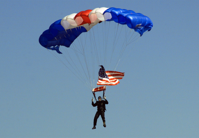 A parachutist with the American flag flys over Freedom Fest 99 at Fort ...