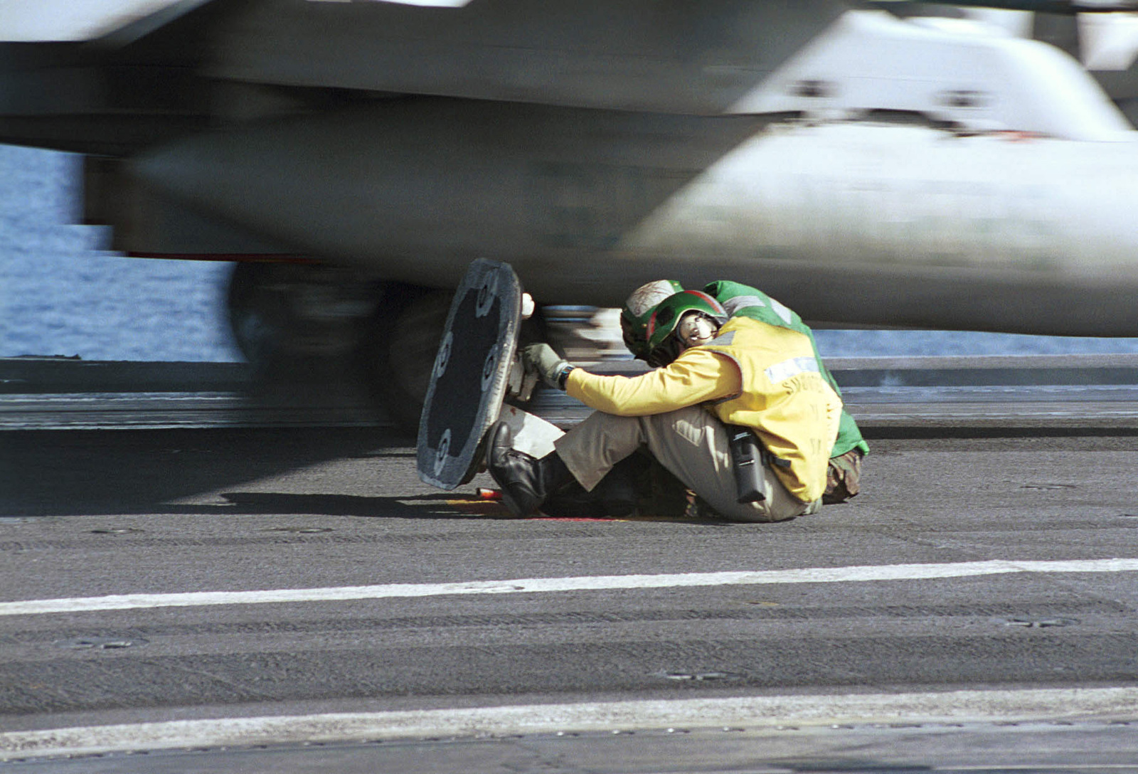 Flight deck crew members brace themselves as an FA-18C Super Hornet ...