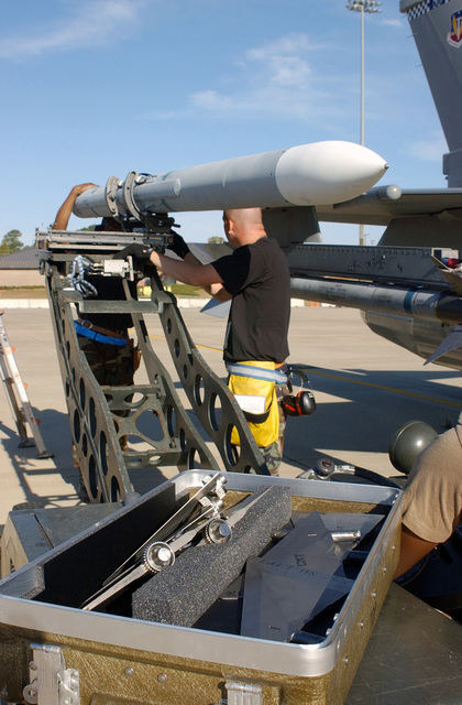 US Air Force (USAF) munitions handlers use an MJ-1 weapons loader to ...