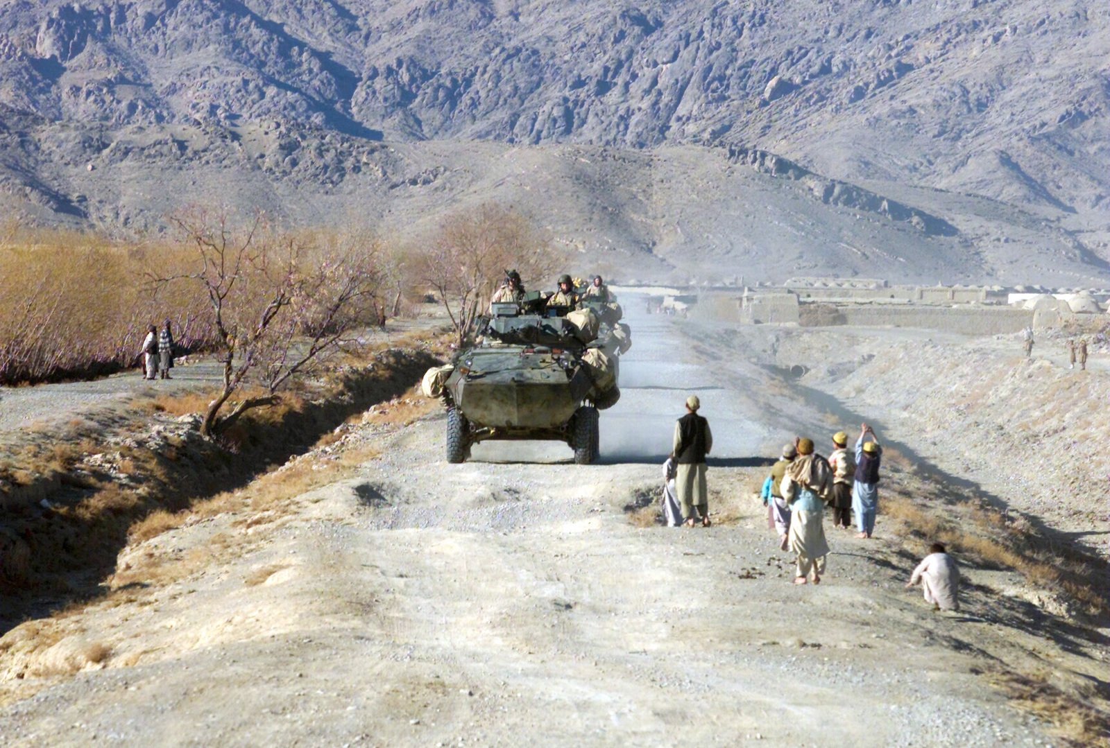 Along the dirt road villagers watch as Marines with Alpha ...