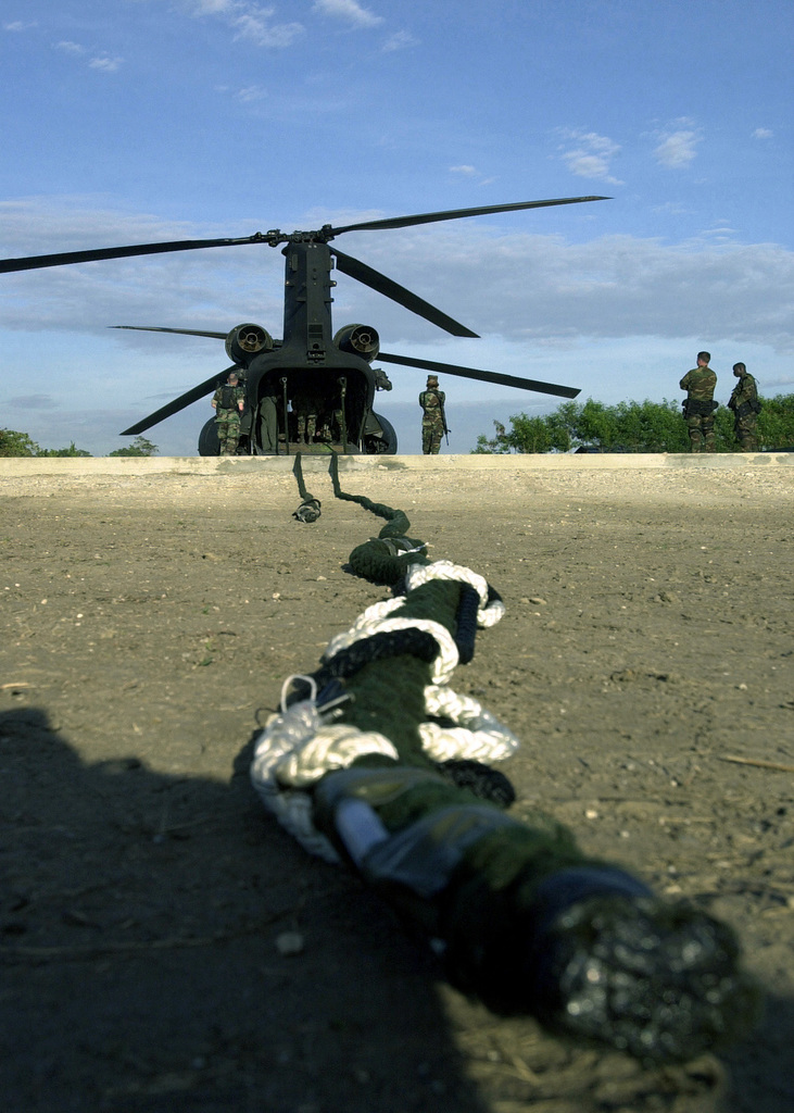 A static line rappelling rope stretches towards a US Army (USA) CH-47E  Chinook helicopter as members of the Philippine Naval Special Warfare Unit  Six and USA soldiers assigned to Joint Task Force