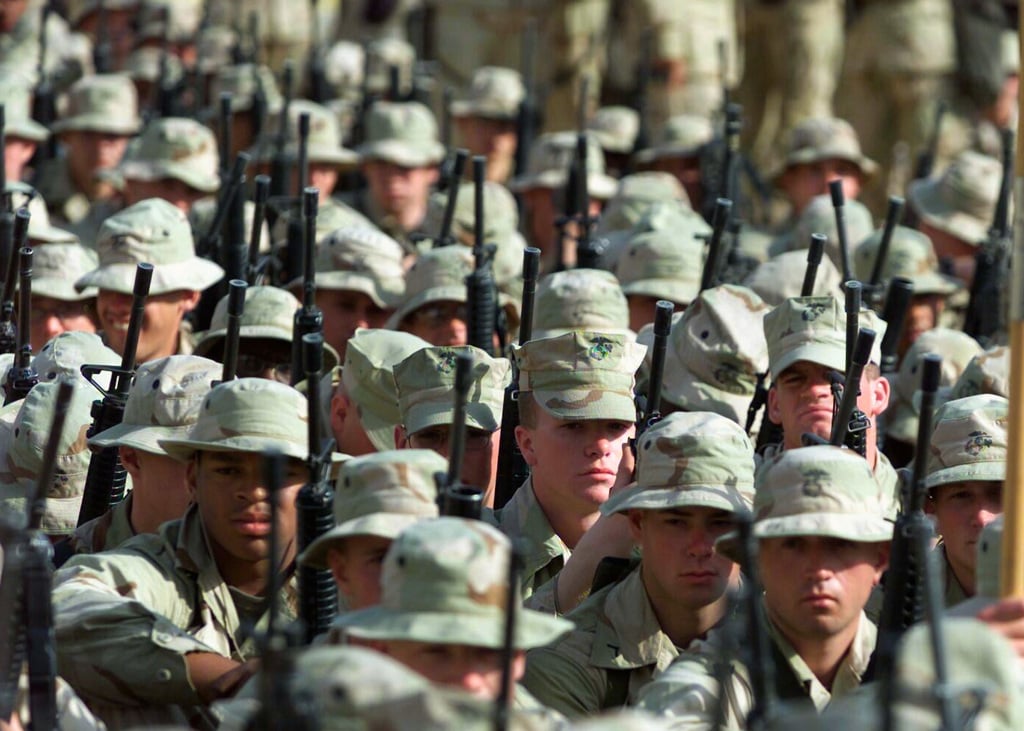 Columns of armed combat ready US Marine Corps (USMC) Marines sit and ...