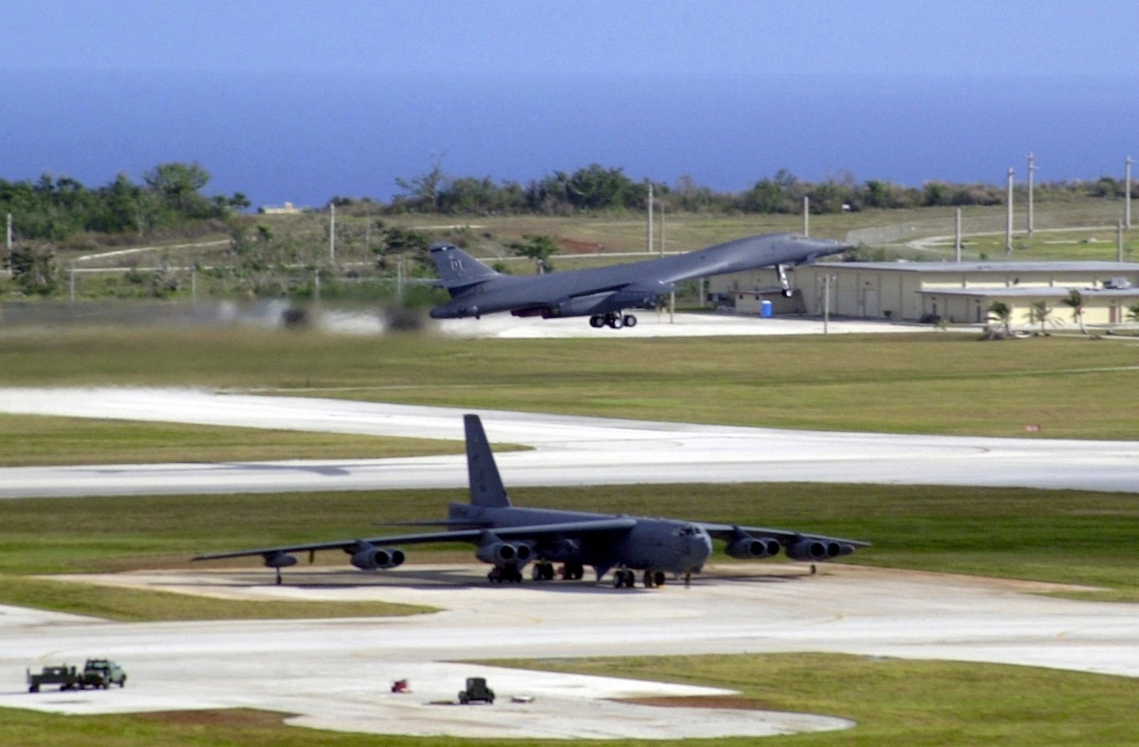 Near a parked US Air Force (USAF) B-52 Stratofortress bomber, a B-1B ...