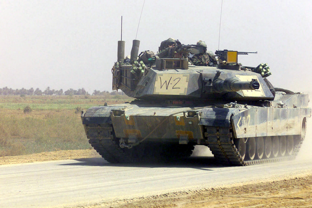 An M1A1 Abrams Main Battle Tank (MBT) rolls down a road and maneuver in ...