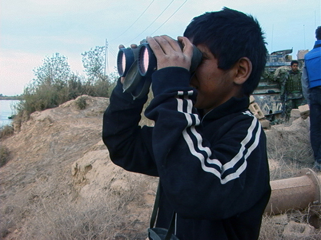 An Iraqi boy tries out a pair of US Marine Corps (USMC) binoculars from ...