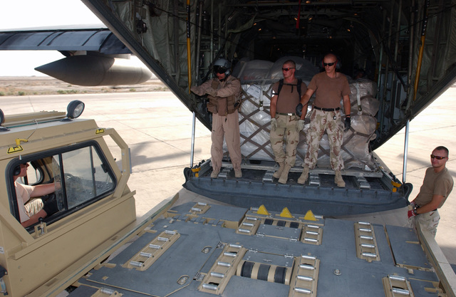 A US Air Force (USAF) C-130 Hercules Loadmaster (left) guides a ...