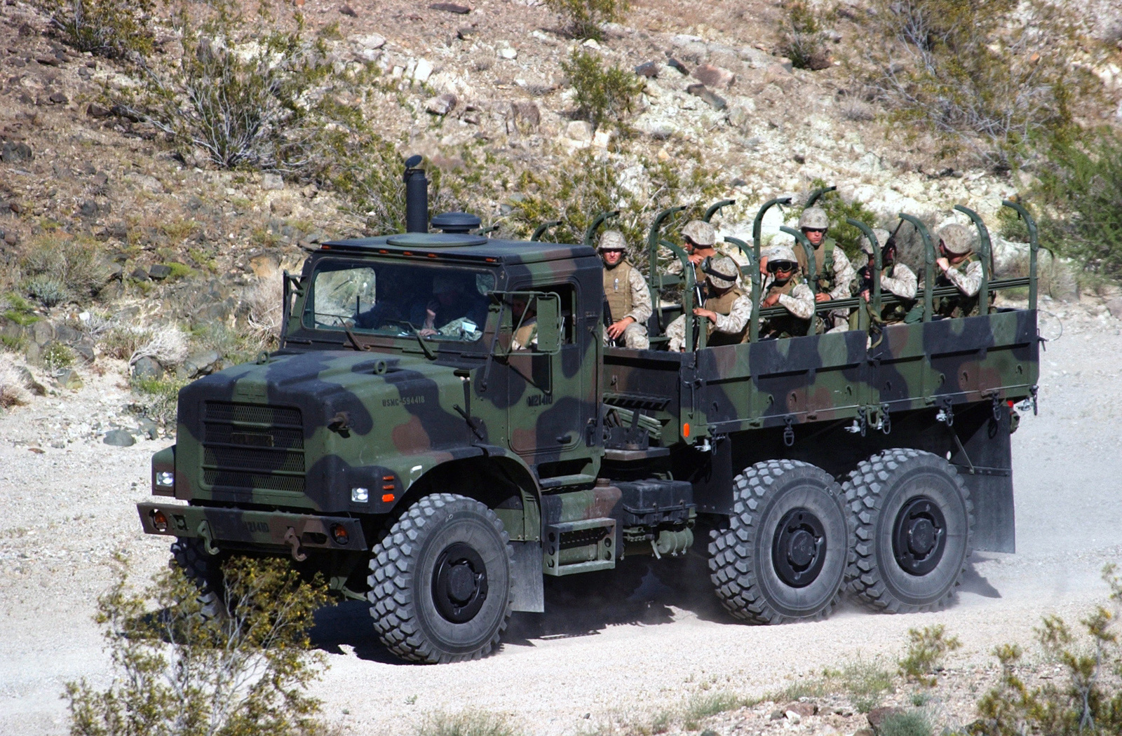 A US Marine Corps (USMC) Bravo Company Co.), 1ST Tanks, MK-23 Medium Tactical Vehicle Replacement (MTVR) 7-ton cargo truck, being used as a carrier, passes slowly through a simulated village