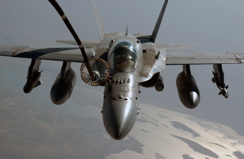 A U.S. Navy F/A-18C Hornet receives fuel from an aerial tanker via ...