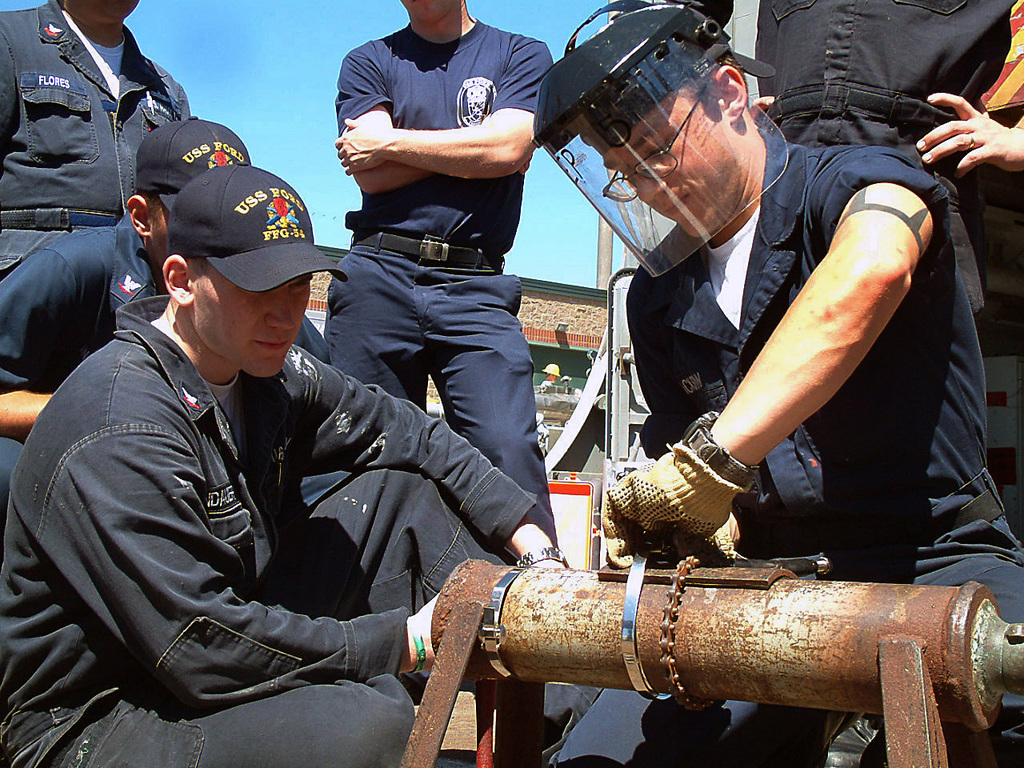 US Navy (USN) Hull Maintenance Technician Fireman (HTFN) Brandon Jackson  (right), and USN Damage Controlman Third Class (DC3) Seth Lindauer  demonstrate pipe-patching techniques and other vital damage control  scenarios in preparation of