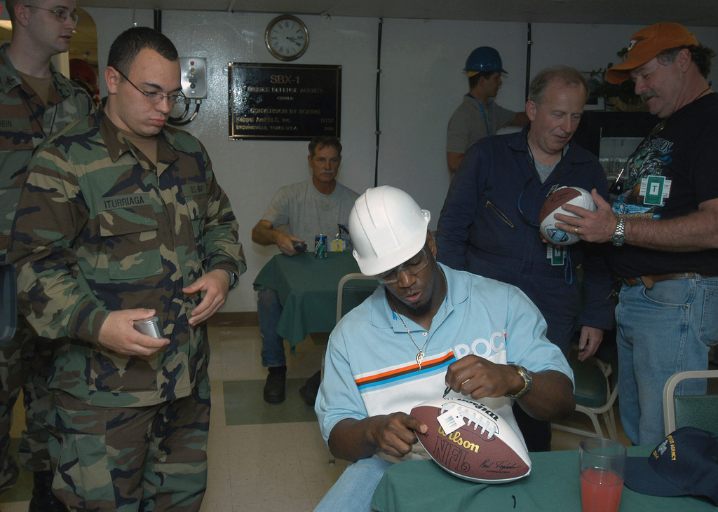 Offensive Tackle for the National Football League (NFL) San Diego Chargers,  Leander Jordan (75), signs an autograph for Aviation Electrician's Mate 3rd  Class Jerimy Holt during a visit aboard USS Ronald Reagan (