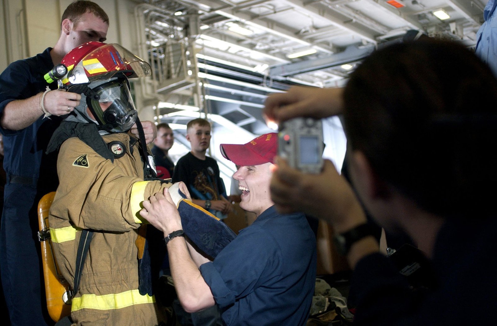 US Navy (USN) Sailors assist Nathan Carlson don a self contained ...