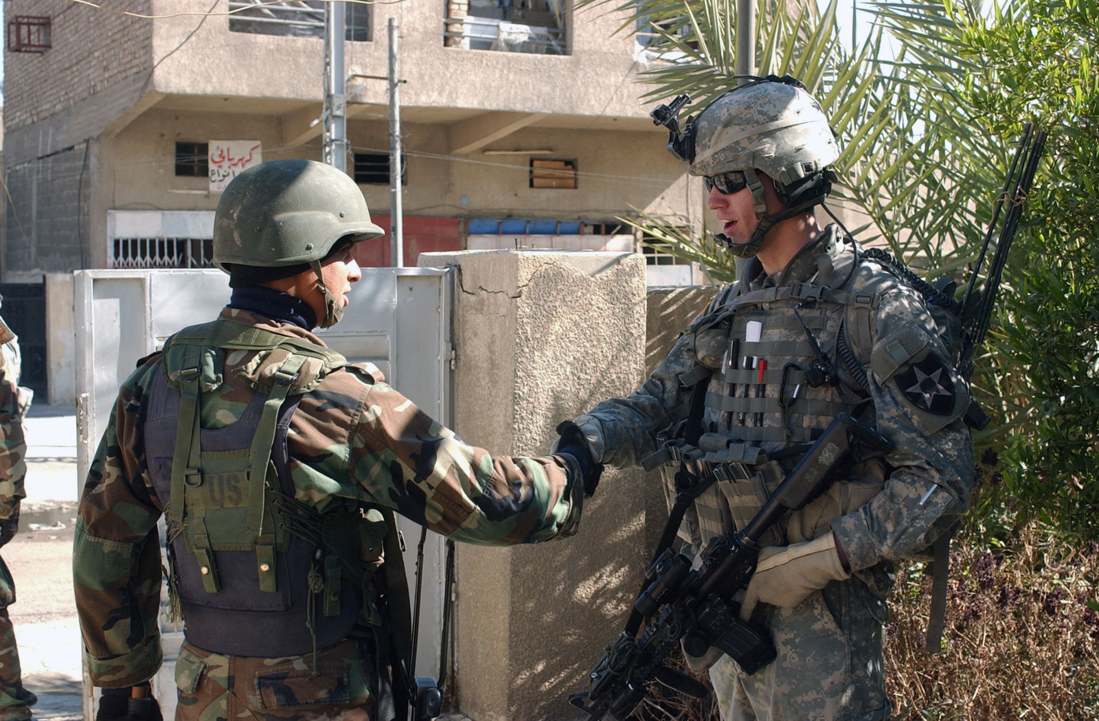 . Army SPC. Chris Hudson, a Radio Telephone Operator with Charlie  Company, 5th Battalion, 20th Infantry Regiment, 2nd Infantry division (ID),  shakes hands with his Iraqi National Police counterpart, after clearing a